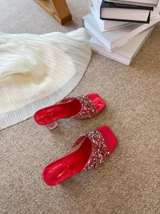 Dettaglio di ciabatte rosse a punta quadrata con strass e tacchi trasparenti