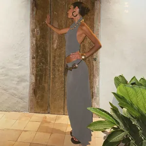 Woman wearing a grey halter backless top and matching long skirt in a rustic setting