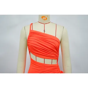 Détail d'une robe orange asymétrique avec des découpes et une texture froncée