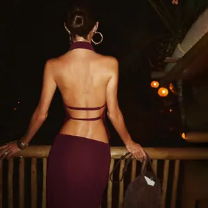 Sexy burgundy halter backless top and skirt set shown from behind in a night setting