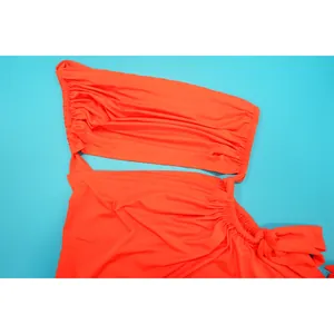 Gros plan d'une robe froncée orange vif à une épaule avec un détail ajouré élégant