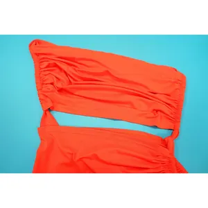 Gros plan détaillé d'une robe orange froncée à une épaule sur un fond bleu ciel éclatant