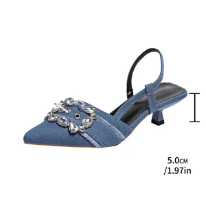 Detailaufnahme der blauen Denim-Sandaletten mit Strassschnalle und 5 cm Absatzhöhe.