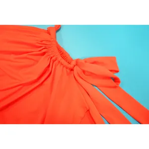 Détail d'une robe orange montrant la texture du tissu et le nœud décoratif.