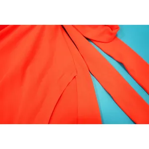 Détail macro montrant des coutures de qualité et une fente haute sur tissu orange vif
