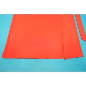 Détail en gros plan de l'ourlet et de la fente latérale de cette robe orange vif