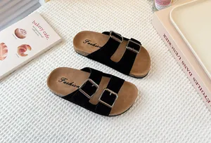 Detalle de sandalias de gamuza negra para niñas con plantillas de corcho y hebillas.