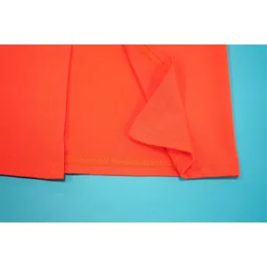 Gros plan détaillé montrant la double couture propre et la structure de l'ourlet de la robe orange
