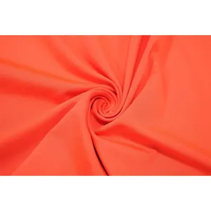 Gros plan détaillé sur un tissu extensible orange vif montrant une texture très lisse.