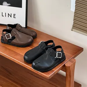 Casual leather sandals for kids in black and brown colors displayed on a wooden shelf