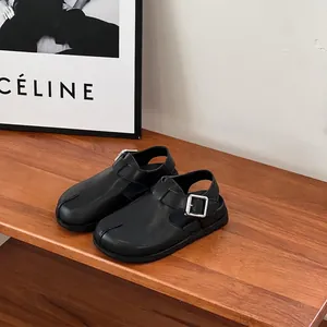 Close-up of black leather children's sandals with split-toe design and buckle strap