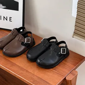 Stylish children's leather closed-toe sandals in brown and black on a wooden shelf