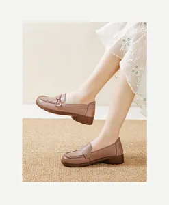 Close-up view of comfortable pinkish-tan leather loafers for women on a rustic woven mat