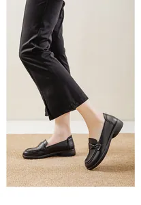 Detail side view of comfortable black slip-on loafers for women on a textured mat