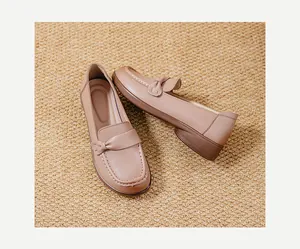 Top view detail of comfortable beige leather women's slip-on loafers on a woven mat