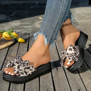 Sandalias de plataforma con estampado de leopardo y lazo grande en suelo de madera