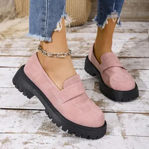 Stylish pink suede loafers with chunky black lug soles shown on a rustic wooden floor