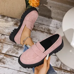 Close-up of pink suede loafers with thick black lug soles in a lifestyle setting