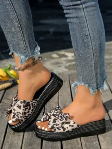 Primer plano de sandalias con plataforma y lazo de leopardo sobre una plataforma de madera