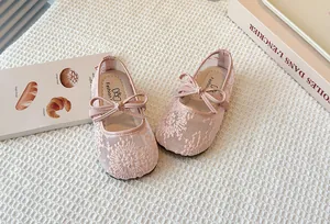Detail view of pink lace mesh children's Mary Jane shoes with bow decoration.
