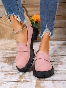 Close-up detail of stylish pink suede loafers with chunky black lug soles on a model