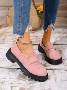 Close-up view of stylish pink suede loafers with thick black lug soles worn by a model