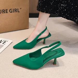 Close-up view of emerald green pointed-toe slingback kitten heels on beige carpet