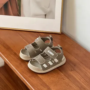 Close-up of khaki toddler sandals with soft soles on a wooden surface