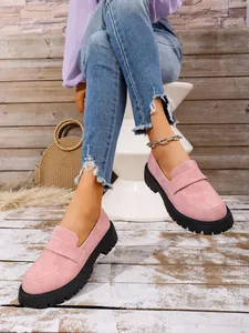 Detailed view of women's stylish pink suede platform loafers with chunky black soles.