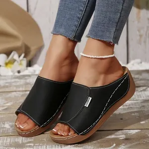 Detailed view of women's black peep-toe wedge slippers with stylish white stitching