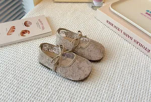 Detailed close-up of girl's beige lace mesh Mary Jane shoes with delicate bow decoration