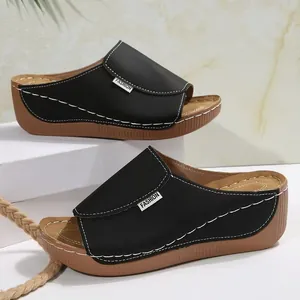 Side view showing the detailed white stitching and fashion label on the black wedge mule.