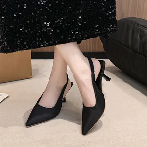 Detail view of black pointed-toe slingback high heels on model.