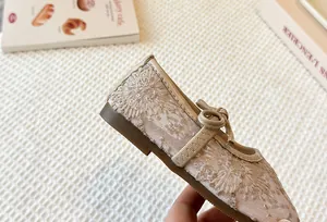 Detail view of the elegant floral lace embroidery and bow on girls' Mary Jane shoe.