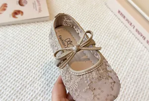 Close-up detail of breathable beige lace mesh girls' Mary Jane shoe with bow.