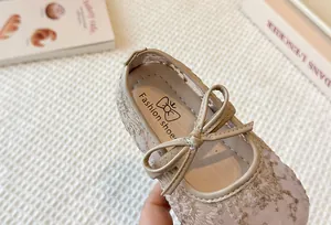 Detail of elegant beige lace mesh girl's Mary Jane shoes with delicate bow decoration