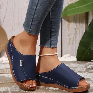 Close-up of navy blue peep-toe wedge slides with white stitching details