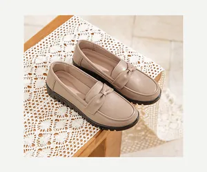 Détail en gros plan de chaussures pour maman en cuir beige avec semelle souple et nœud.