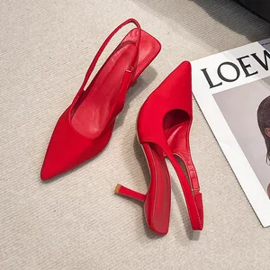 Detailed top view of red pointed-toe slingback high heels on a neutral textured floor