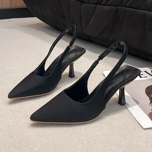 Side view of elegant black pointed-toe slingback high heels on white carpet