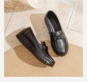 Détail de chaussures en cuir noir pour maman avec nœud décoratif et semelle plate et souple