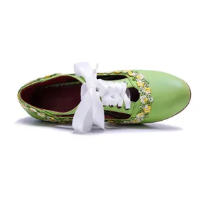 Top-down view of green vintage Mary Jane heels with delicate lace trim and white ribbon bow.