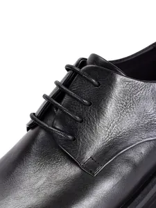 Detalle macro de alta calidad que muestra la textura del cuero negro genuino y los cordones