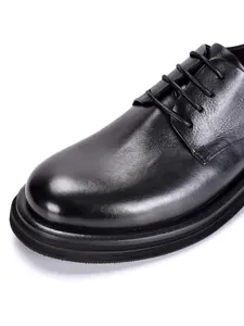 Detalle de zapatos de vestir de cuero genuino negro para hombre con grano de alta calidad.