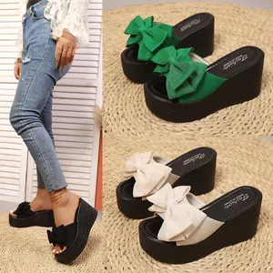Sandalias de cuña de verano con grandes lazos decorativos en verde, beige y color negro.