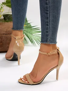 Elegant nude patent leather stiletto sandals with adjustable ankle strap shown on feet