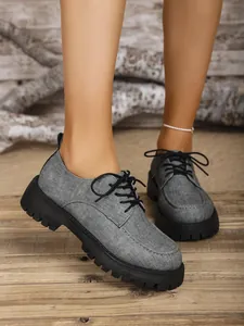 Detail von grauen Oxford-Schuhen mit Plattform und schwarzer Schnürung für Damen