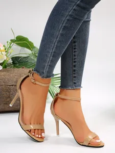 Side detail of women's nude patent leather stiletto sandals with an ankle strap