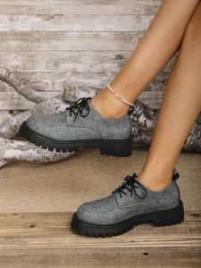 Detail von grauen Denim-Loafern mit dicken schwarzen Profilsohlen in rustikalem Ambiente