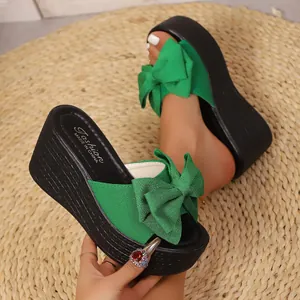 Primer plano de sandalias de cuña verdes con un lazo decorativo grande en alfombra